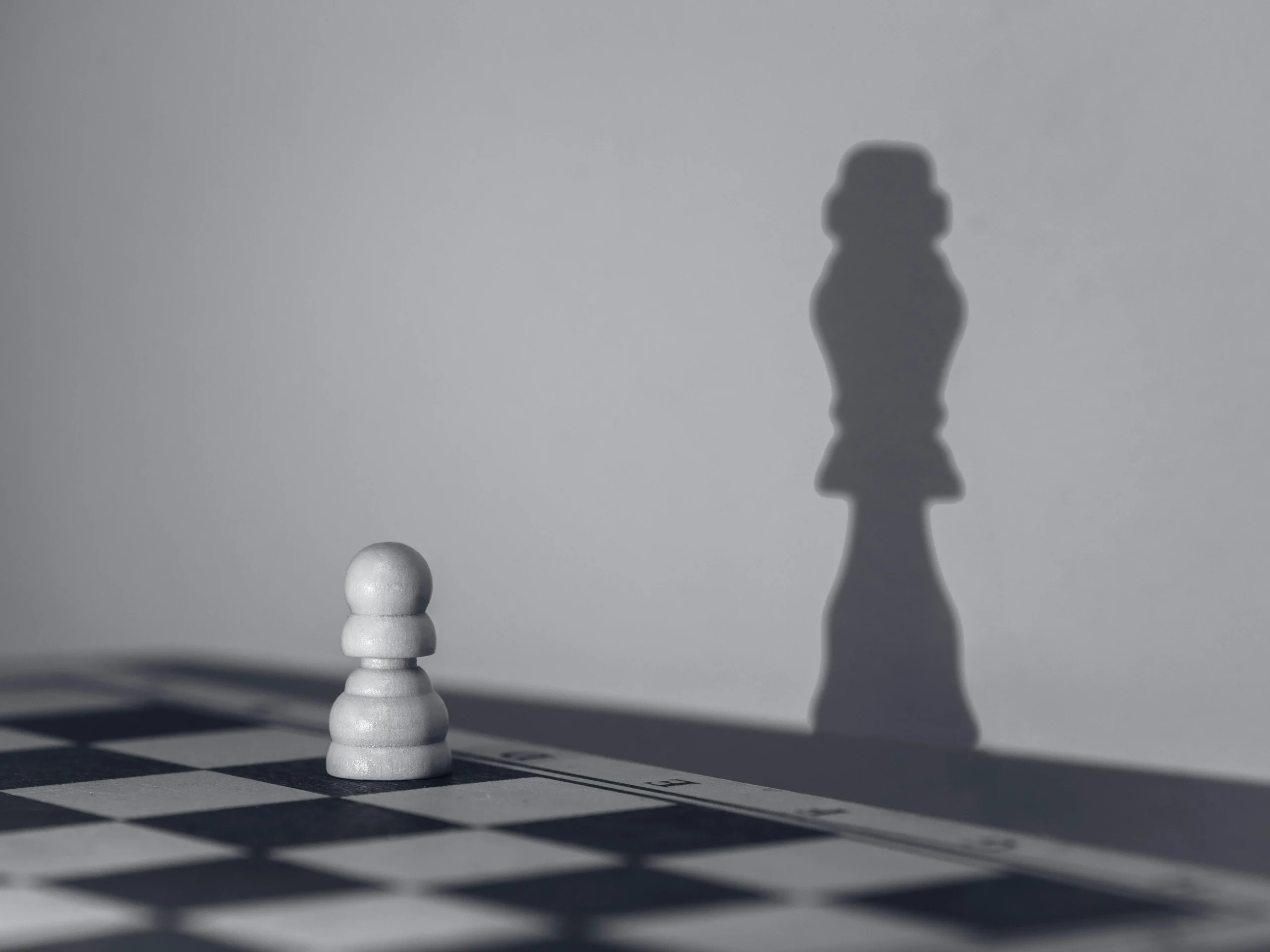 Image représentant un échiquier avec une petite pièce et l'ombre d'une grande dans le mur